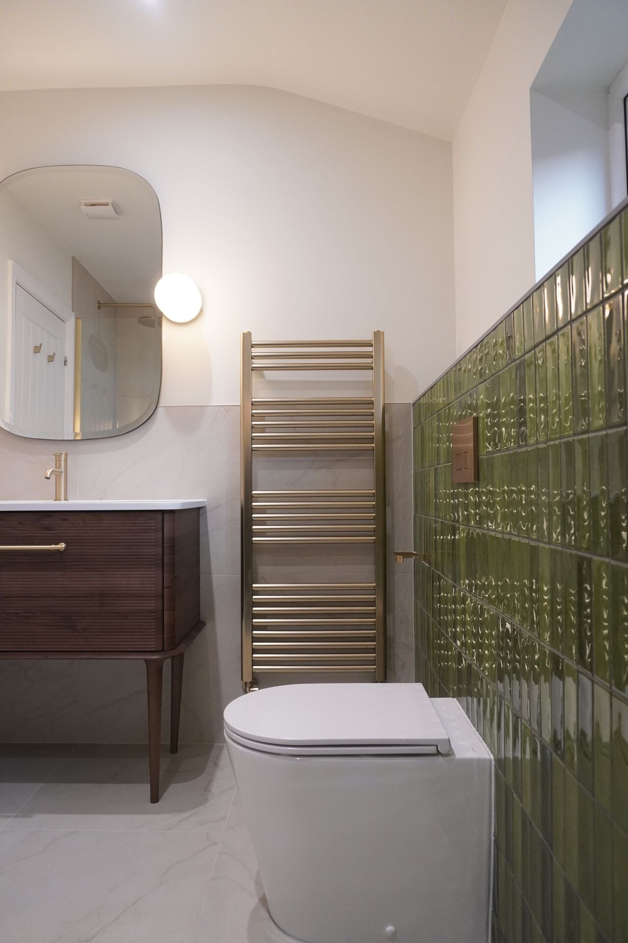 Bathroom with green glazed tile and brass towel rail