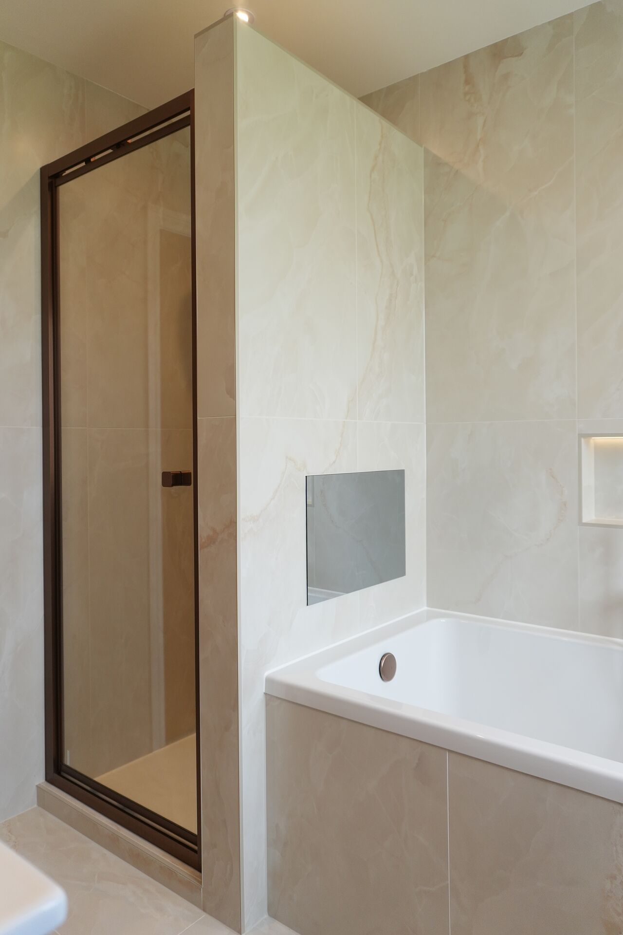 Built-in bath with concealed television and onyx-effect tiling