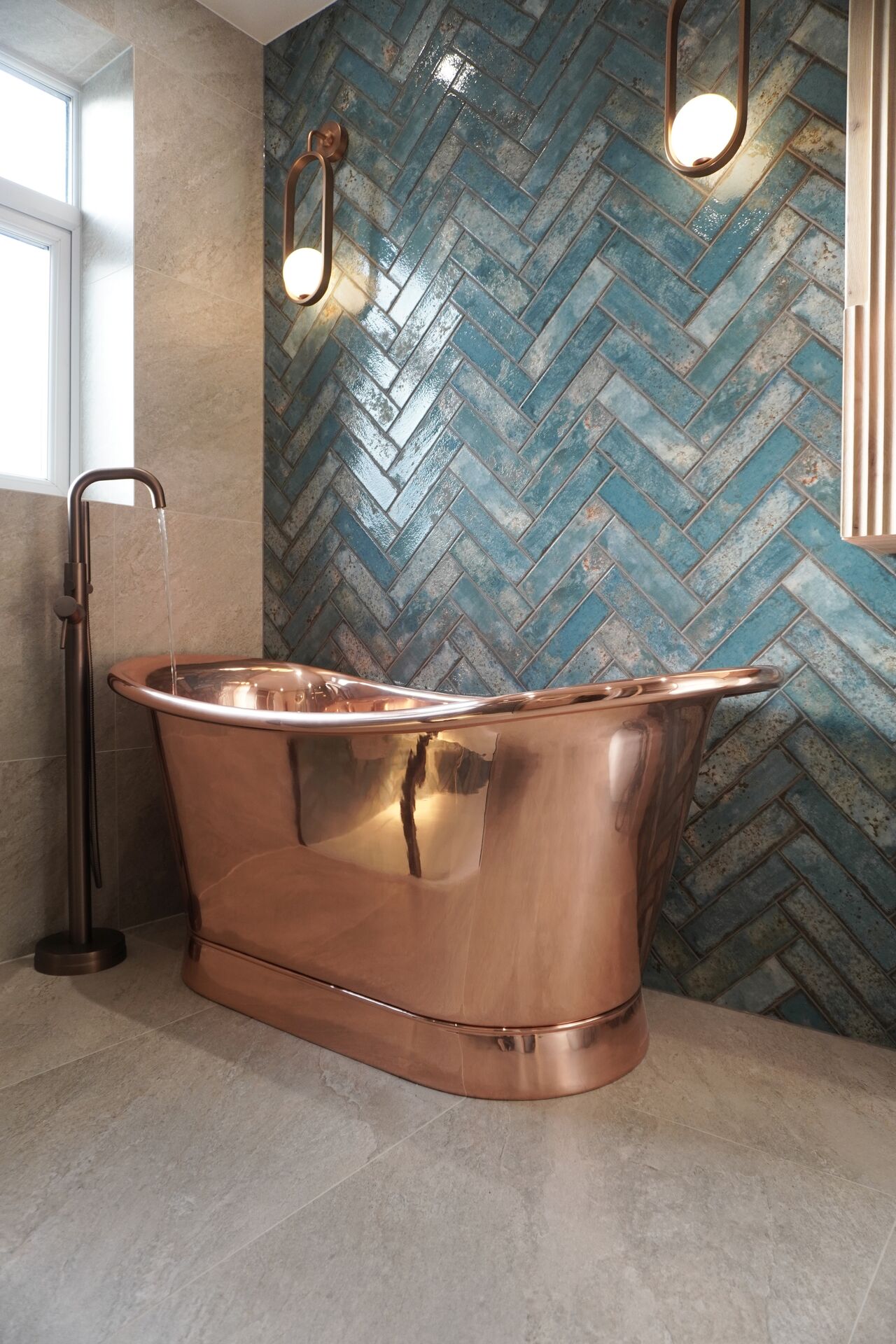Copper freestanding bath with blue herringbone tiling