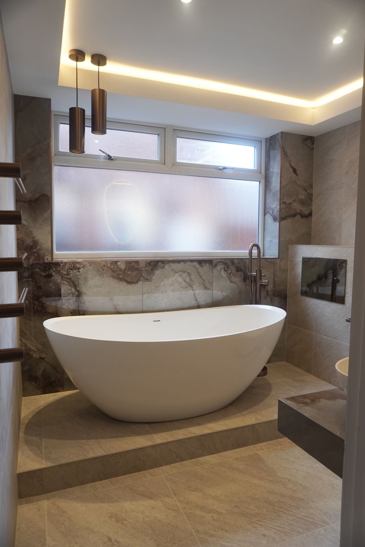 Freestanding bath beneath brass pendant lighting