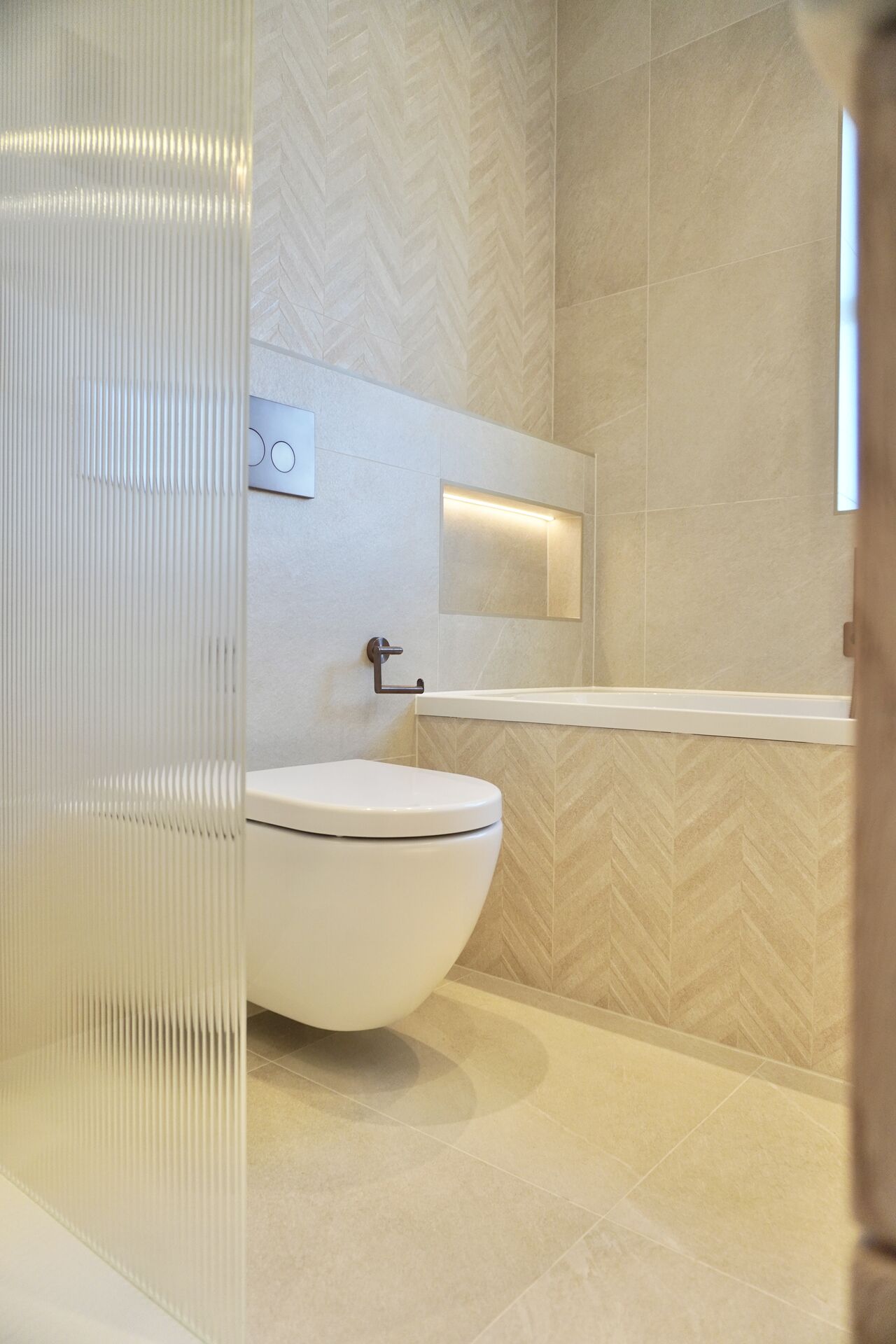 Herringbone tiled bathroom with recessed niche lighting